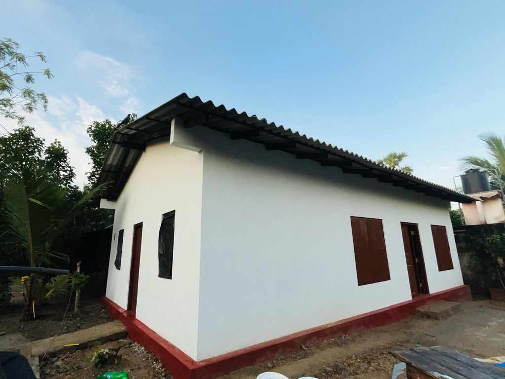 Das gespendete Haus in Vaddukoddai bei Jaffna mit weissen Wänden, rotem Sockel und Wellblechdach.
