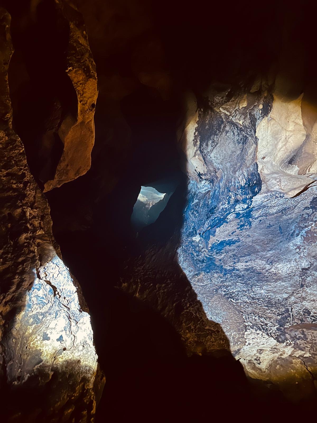 Licht beleuchtet die strukturierten Felswände eines dunklen Höhlengangs in Kambodscha.