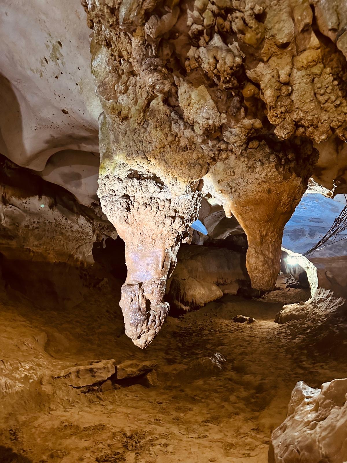 Beleuchtete Tropfsteinformationen hängen von der Decke einer Höhle in Kambodscha.